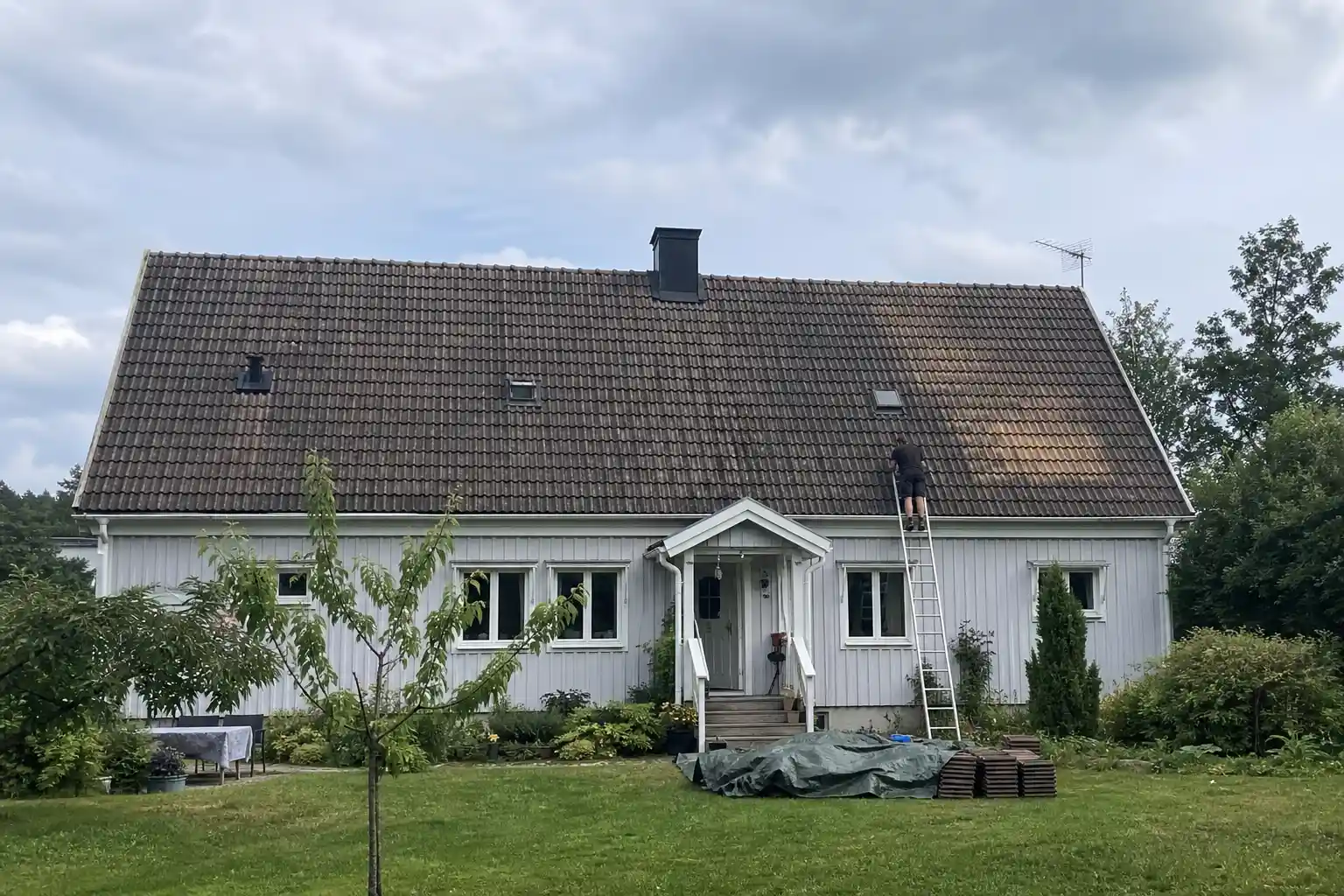 Villatak med slitna takpannor och stege lutad mot taket inför beslut om att byta eller renovera tak
